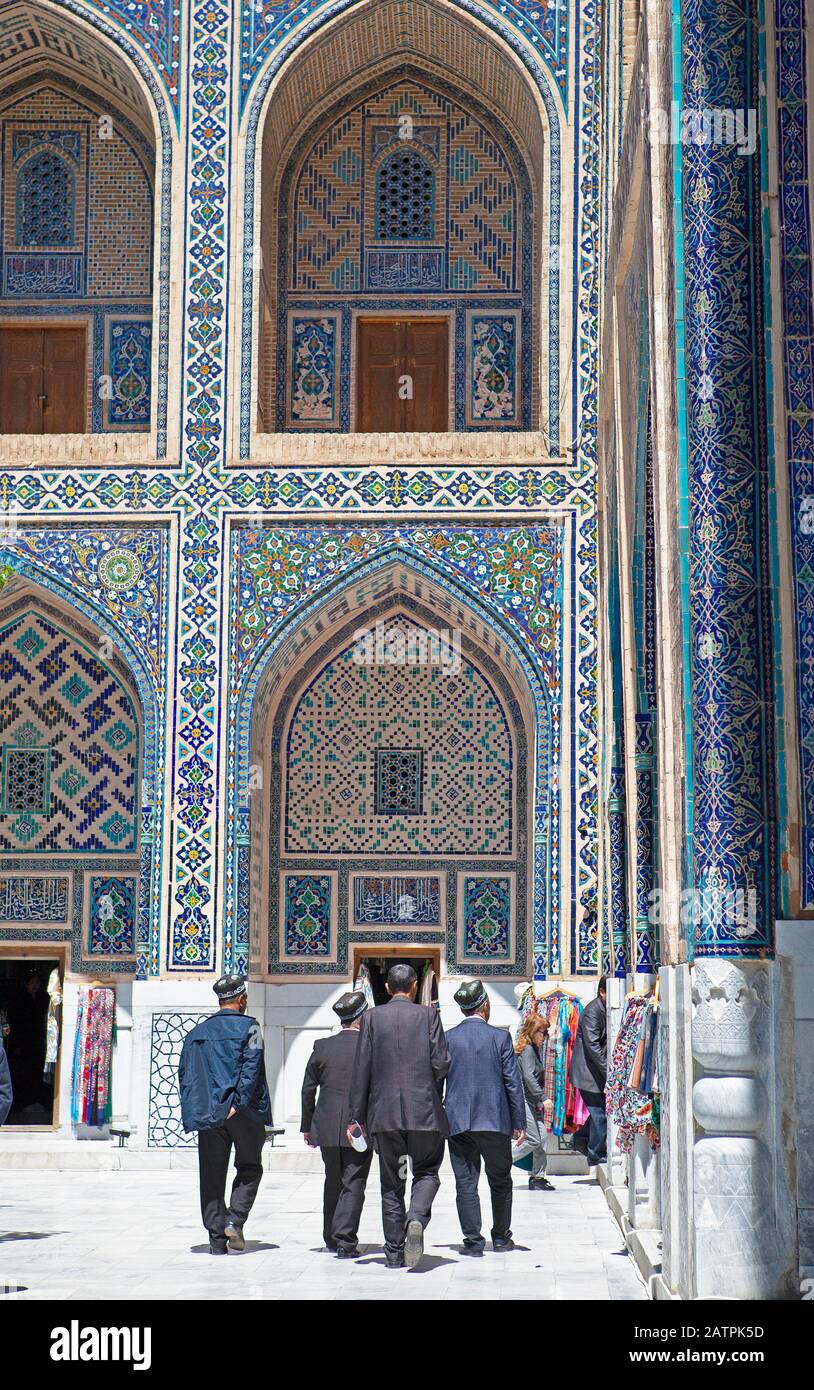 Men with Doeppi in the courtyard with pointed arch niches of the Ulug'Bek-Medrese, Registan Square, Samarkand, Samarqand Province, Uzbekistan Stock Photo