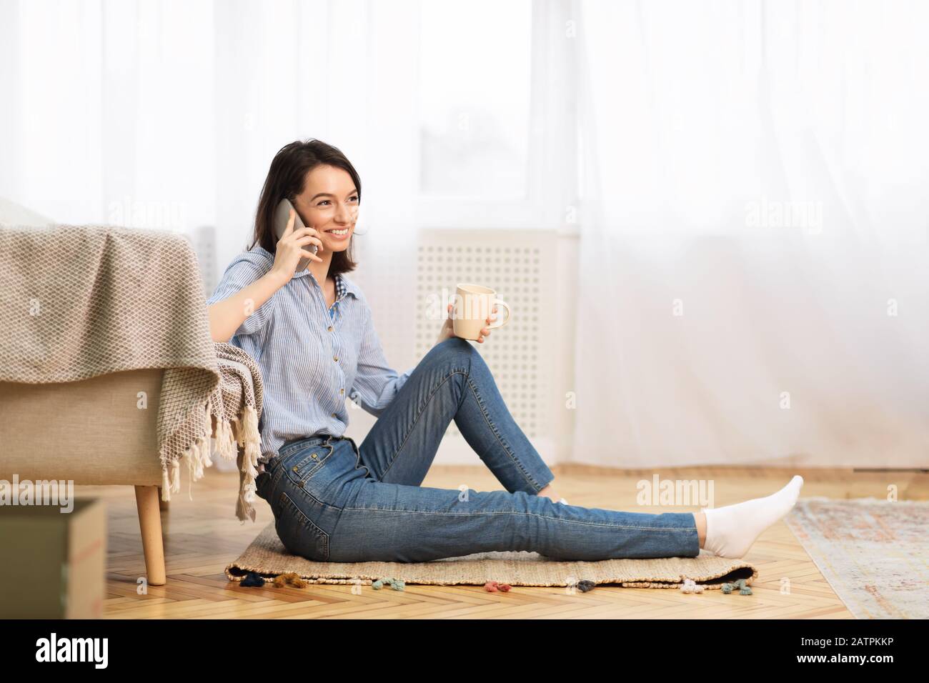 Young woman drinking coffee talking on mobile phone Stock Photo