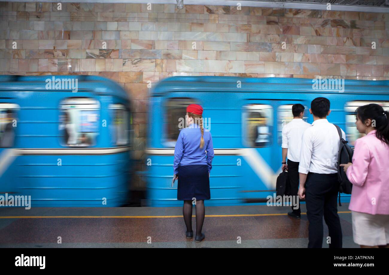 Conductor in uniform and passengers waiting at the passing train, Tashkent metro station, Tashkent province, Uzbekistan Stock Photo
