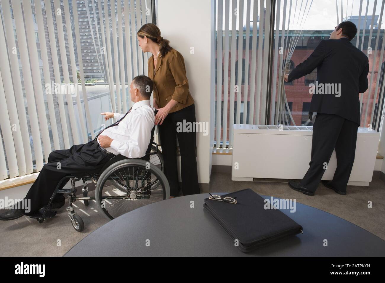 Three business executives looking through windows in an office Stock Photo