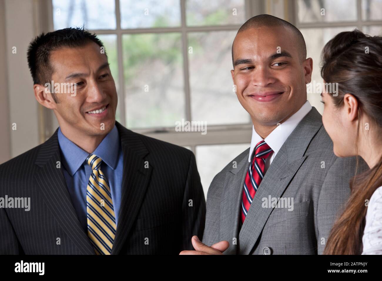 Portrait of three young professionals standing and talking Stock Photo ...