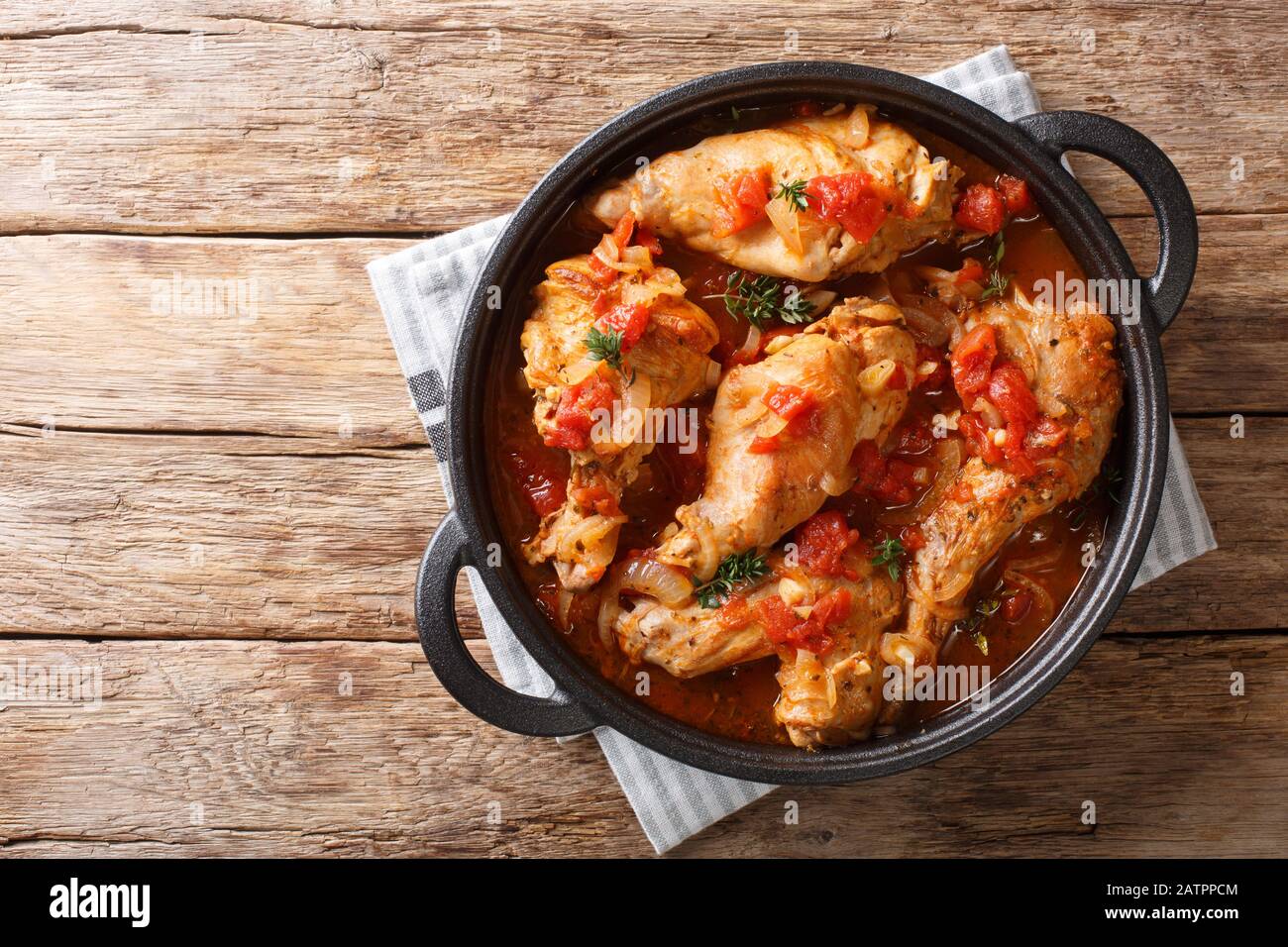 Tasty spicy rabbit stew in tomato sauce with white wine and herbs close-up in a pan on the table. Horizontal top view from above Stock Photo