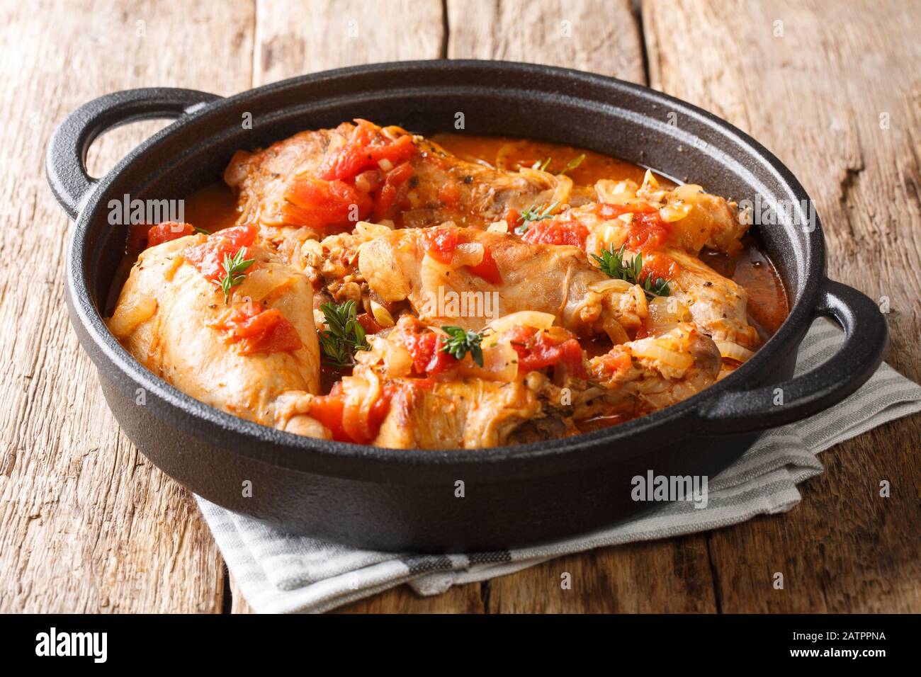 Tasty spicy rabbit stew in tomato sauce with white wine and herbs close-up in a pan on the table. horizontal Stock Photo