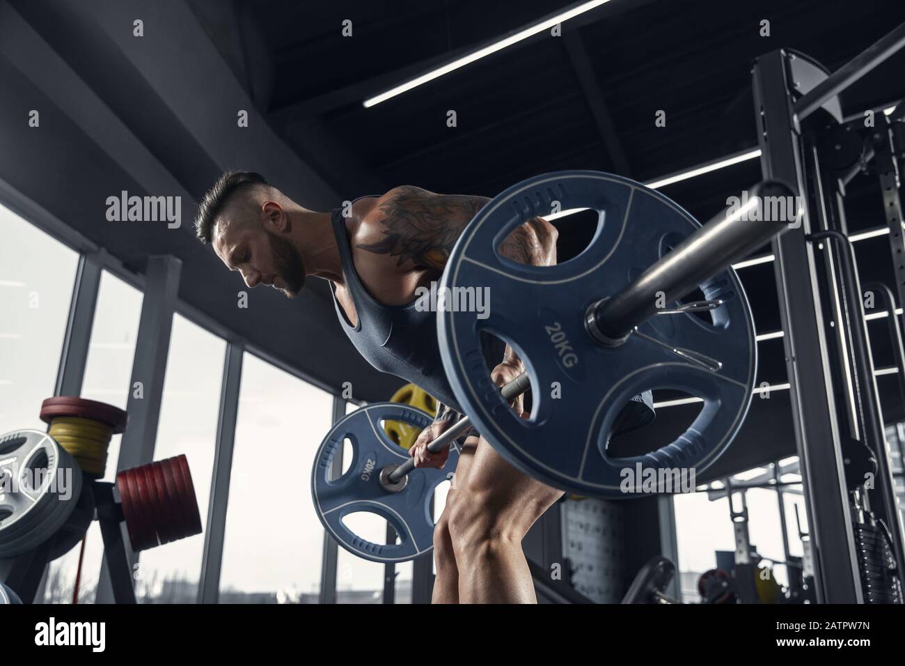 Powerful. Young muscular caucasian athlete practicing pull-ups in gym ...