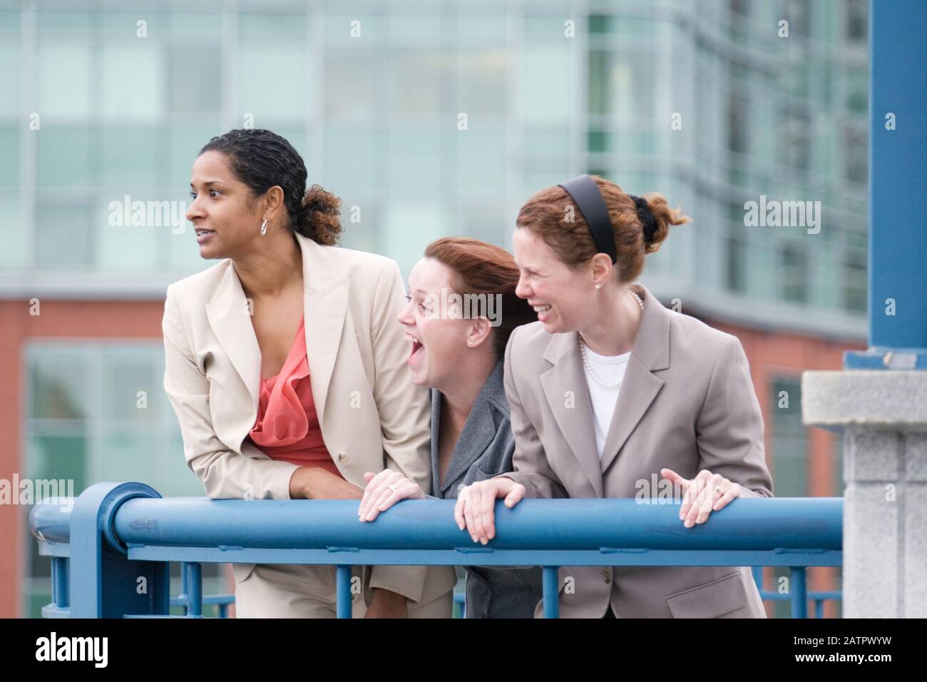 Three women standing by railing and laughing Stock Photo - Alamy