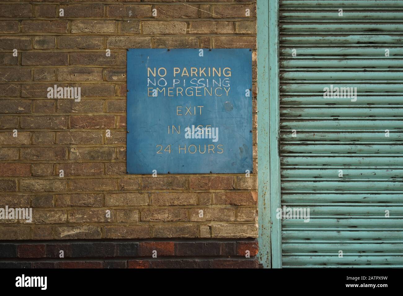 No Parking Sign on a Brick Wall with a Garage Door Stock Photo
