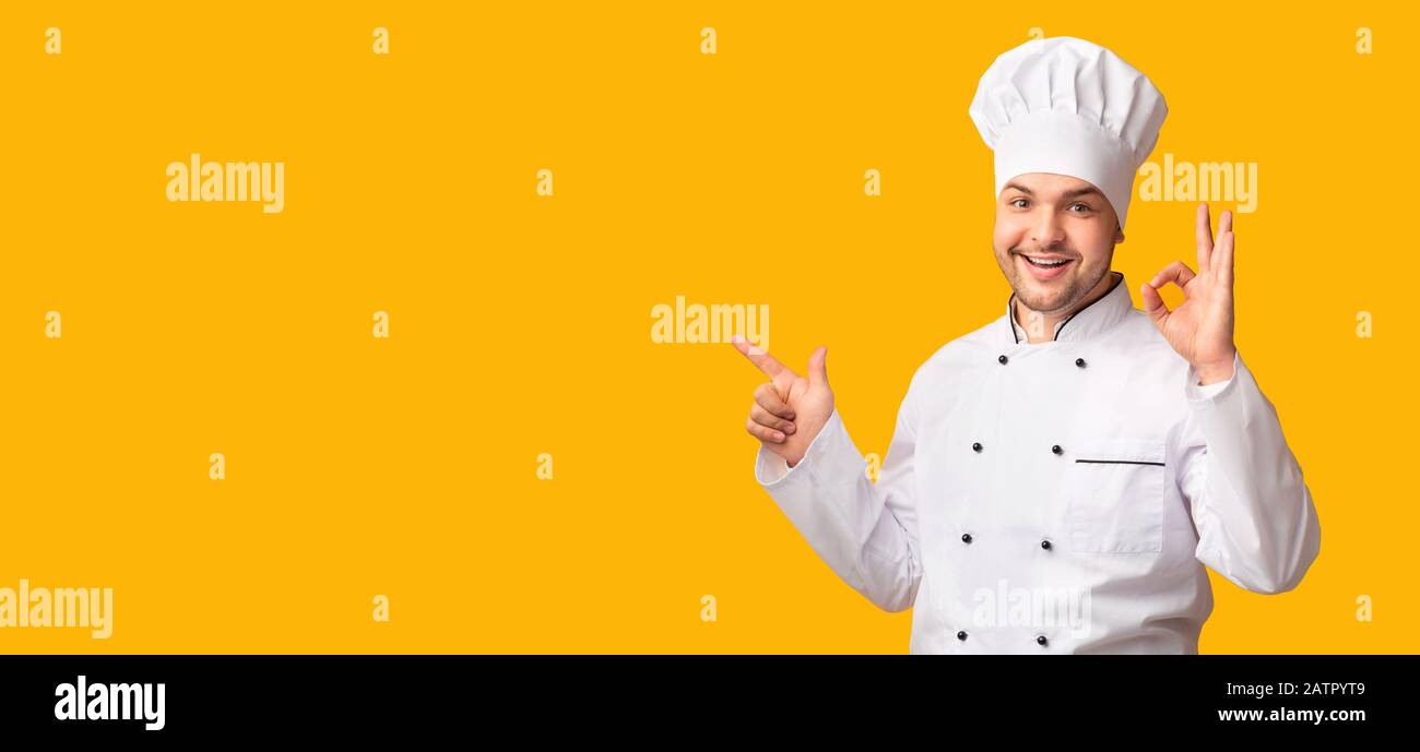 Chef Gesturing Okay Pointing Finger At Copy Space, Yellow Background Stock Photo