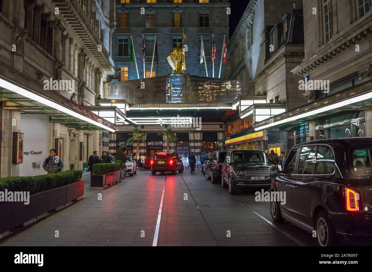 The Savoy Hotel in London at night on The Strand with black taxis parked up Stock Photo