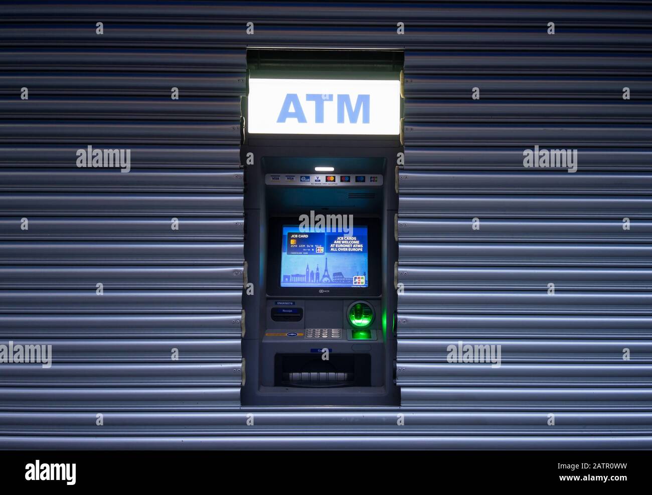 ATM Cash withdrawal machine inside the metal shutters of a shop window Stock Photo