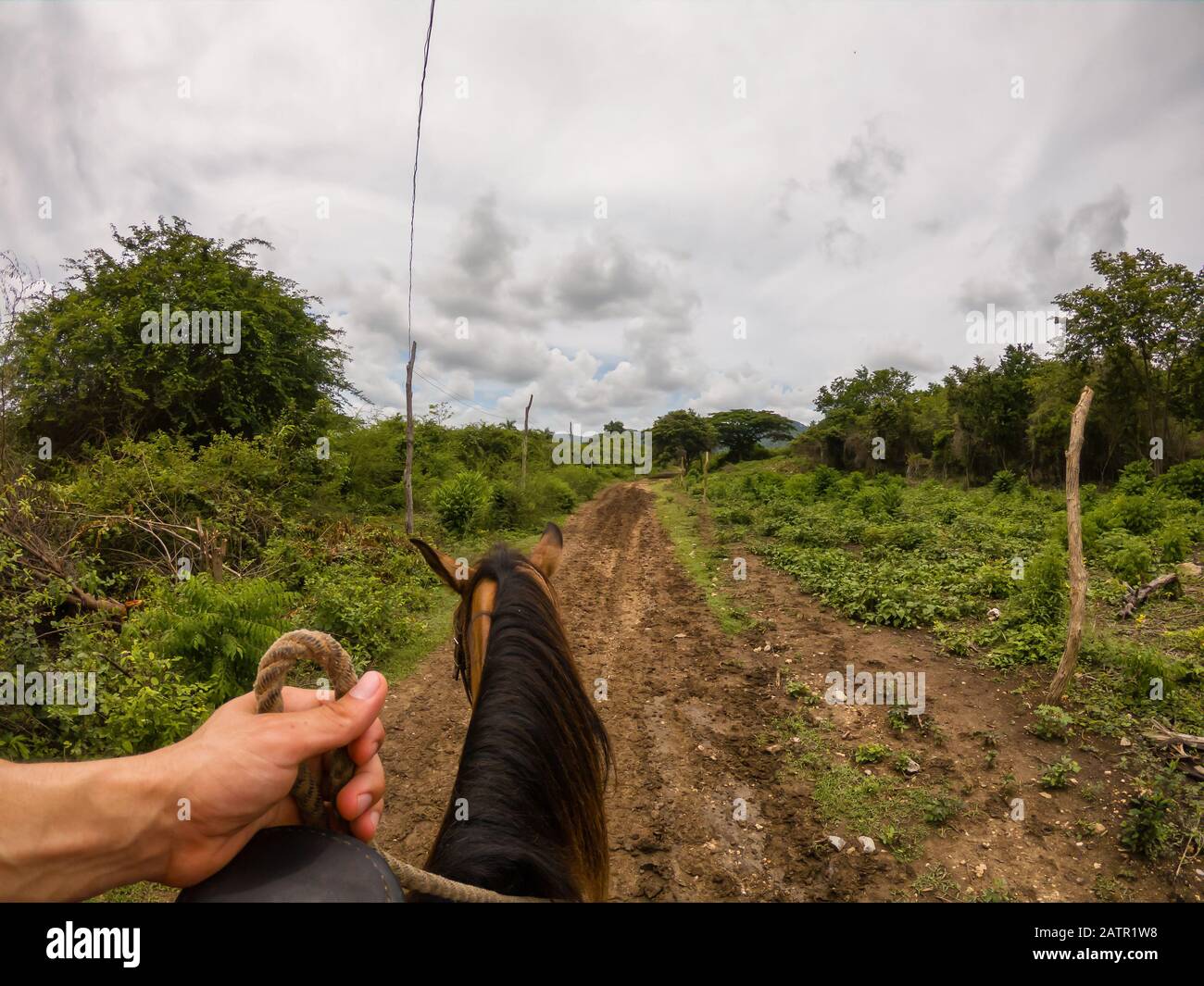 Horseback Riding on a dirty trail in the country side near a small Cuban Town during a vibrant sunny day. Taken in Trinidad, Cuba. Stock Photo