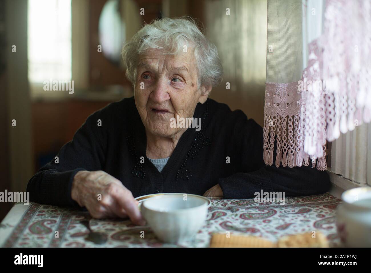 Portrait of old woman sitting at a table in the house Stock Photo - Alamy