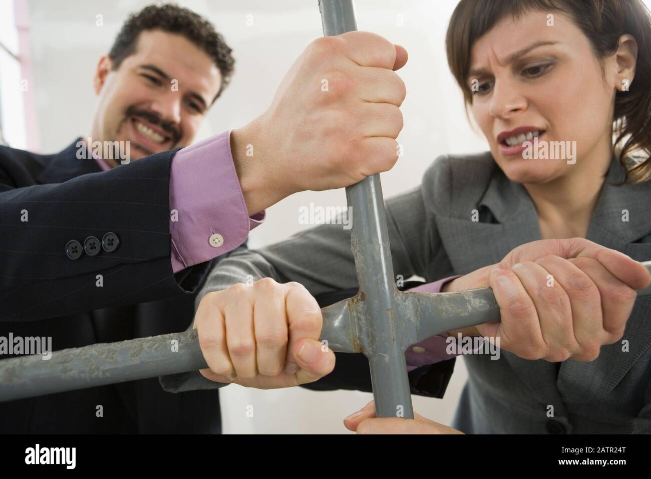 Businessman and a businesswoman gripping the rod of a scaffolding Stock Photo