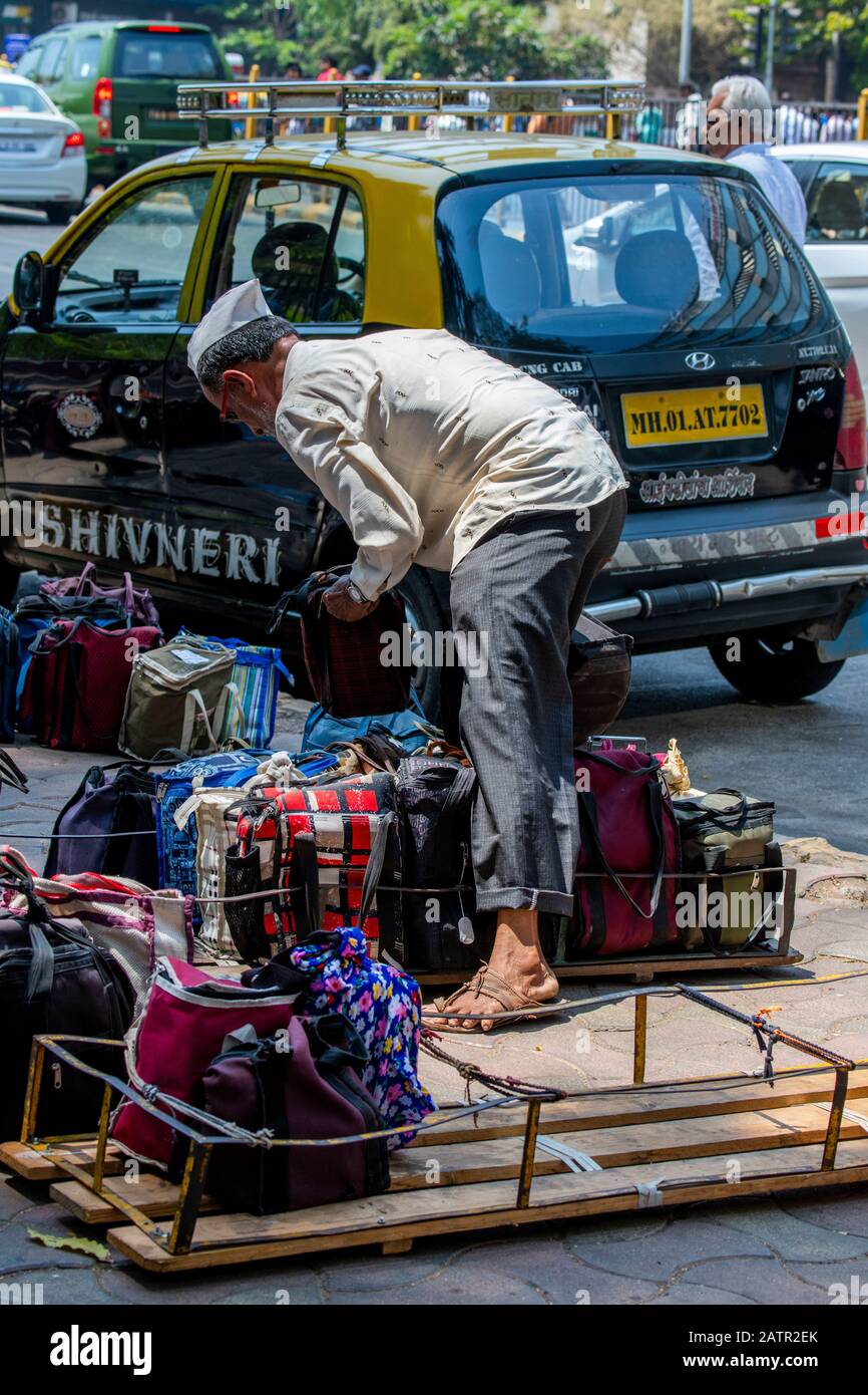 India, Mumbai aka Bombay. Dabbawalas (aka dabbawallas or dabbawallahs, tiffin wallahs) deliver lunches all over the city every day. Sorting meals on t Stock Photo
