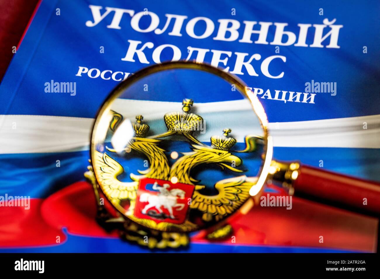The Criminal code of the Russian Federation is under under a magnifying glass. The book's cover reads in Russian 'Criminal Code of the Russian Federat Stock Photo