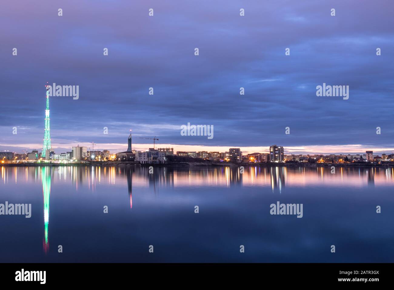 Long exposure photo of a beautiful sunset at Lacul Morii Lake with urban buildings in the background and a tower that looks like a Christmas tree - La Stock Photo