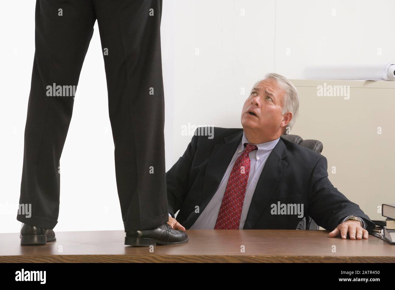 Low section view of a businessman standing on the table with another businessman looking at him Stock Photo
