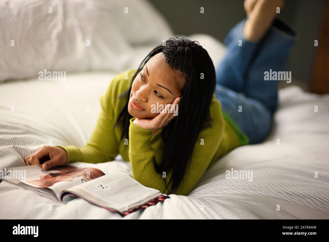 Teenage girl lying on her bed day dream while reading a magazine Stock