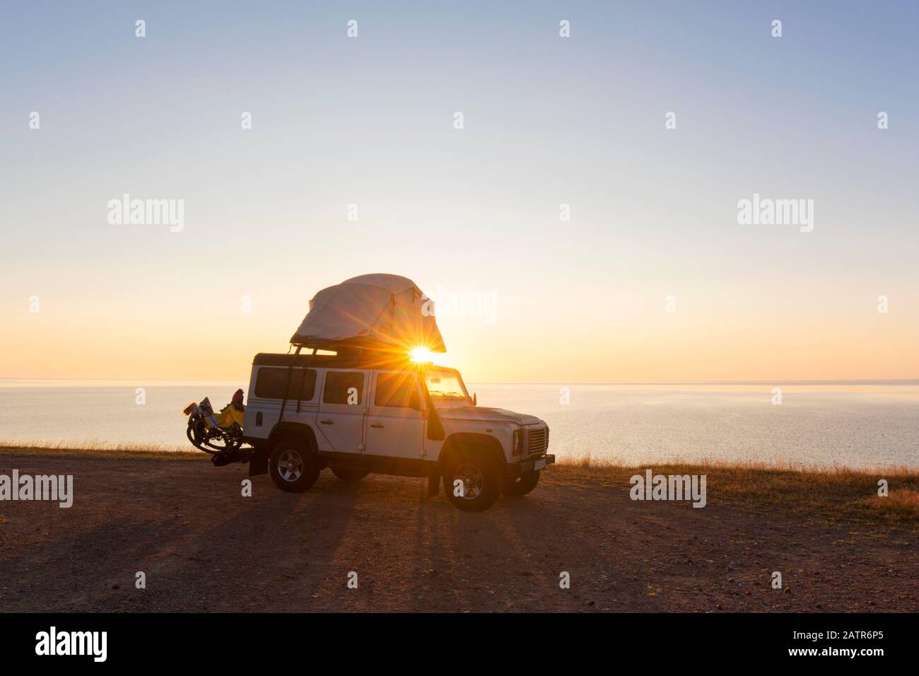 Off-road four-wheel drive vehicle with rooftop tent camping along the Baltic Sea at sunrise in summer, Skåne / Scania, Sweden Stock Photo