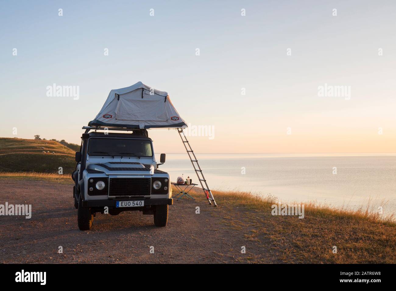 Off-road four-wheel drive vehicle with rooftop tent camping along the Baltic Sea at sunrise in summer, Skåne / Scania, Sweden Stock Photo