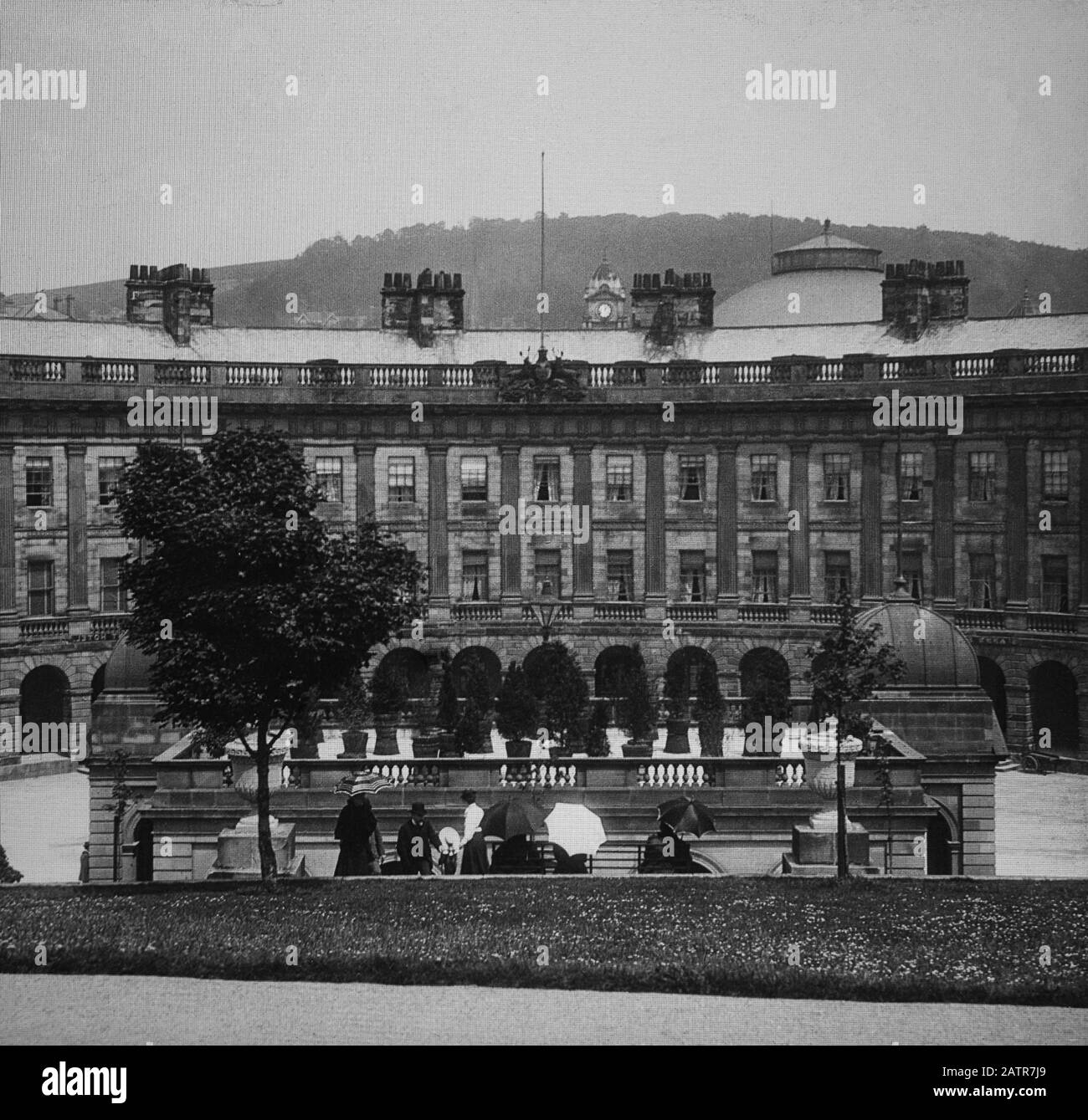 Buxton Crescent & Thermal Spa Hotel during the Victorian period c1890, Victorians in front of the Bath House, antique old glass magic lantern slide picture. The newly renovated hotel is due to open in 2020 creating a northern capital for health and wellbeing. Antique Magic Lantern Slide.  Original photographer unknown, copyright period expired.  Digital photography, restoration, editing copyright © Doug Blane. Stock Photo