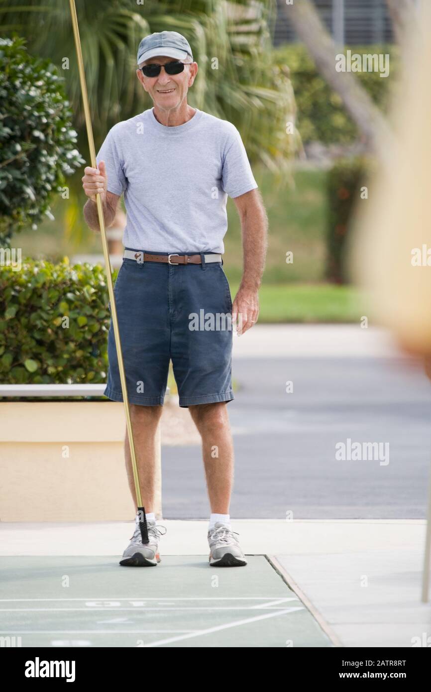 Senior man playing shuffleboard Stock Photo - Alamy