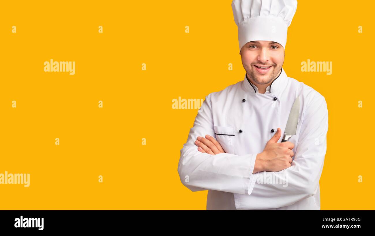Cook Guy Holding Kitchen Knife Standing Over Yellow Background, Panorama Stock Photo