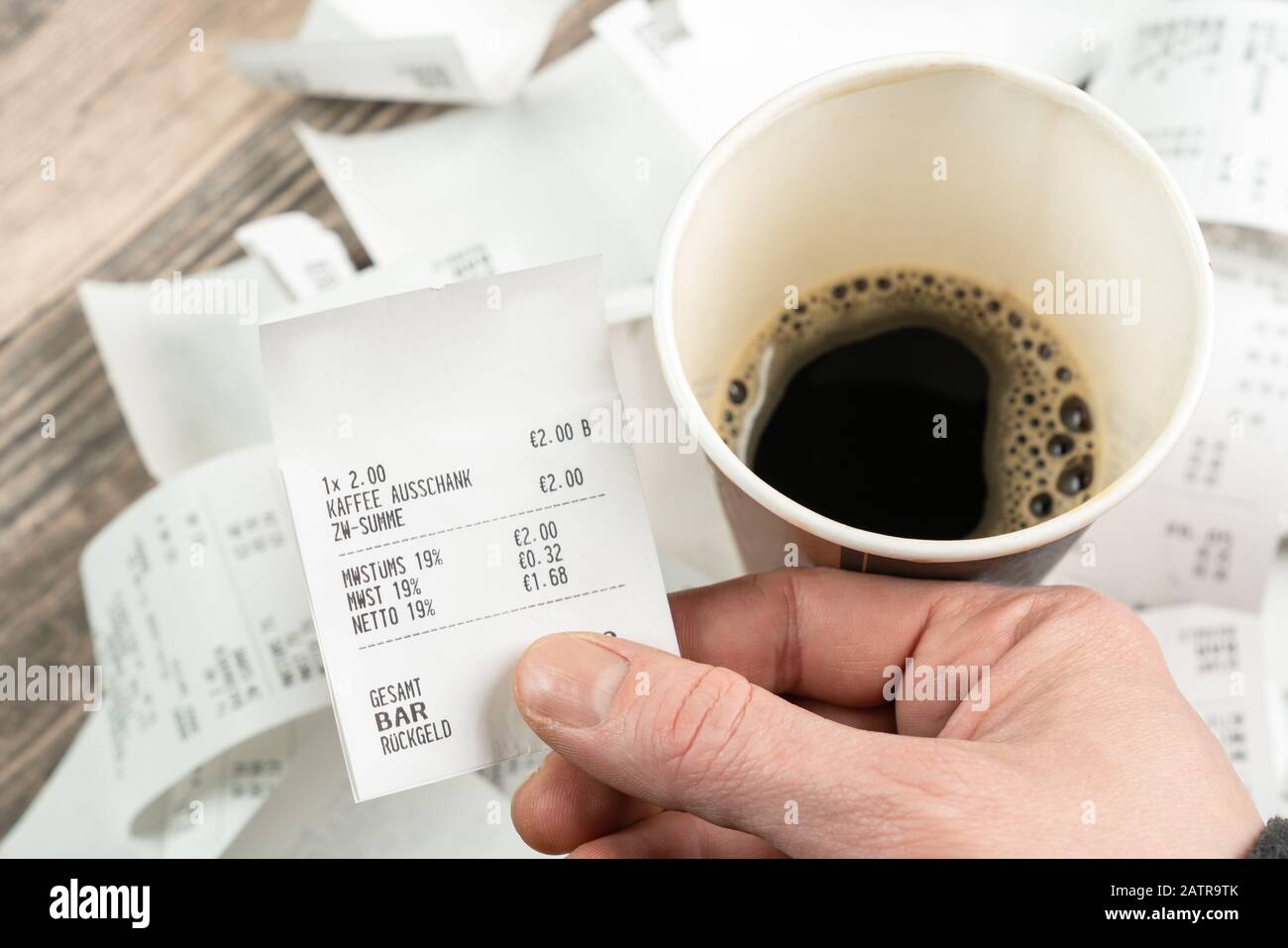 a person with a coffee holds a receipt in his hand Stock Photo