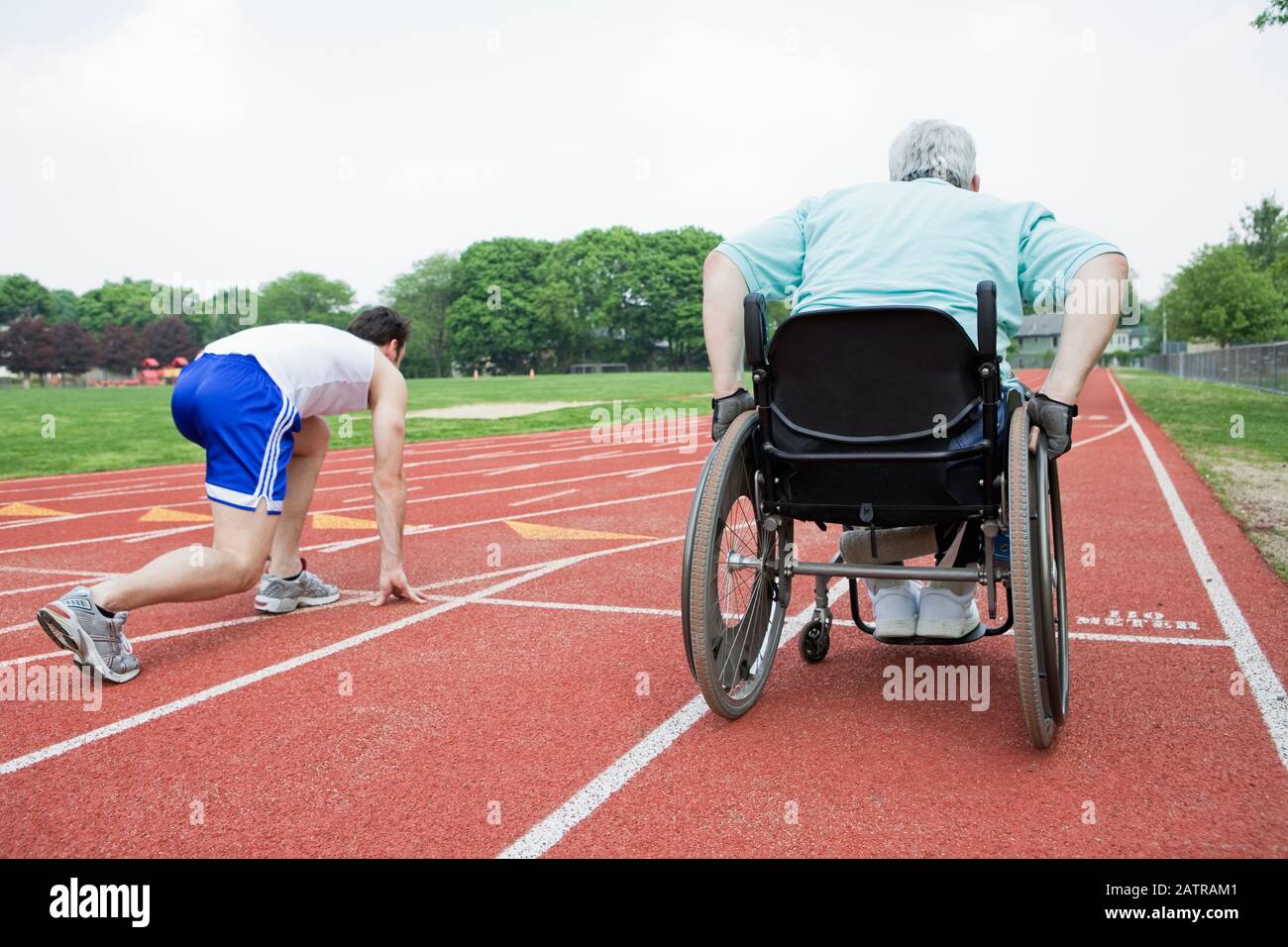 Rear view of a young man racing with a handicapped senior man on a ...