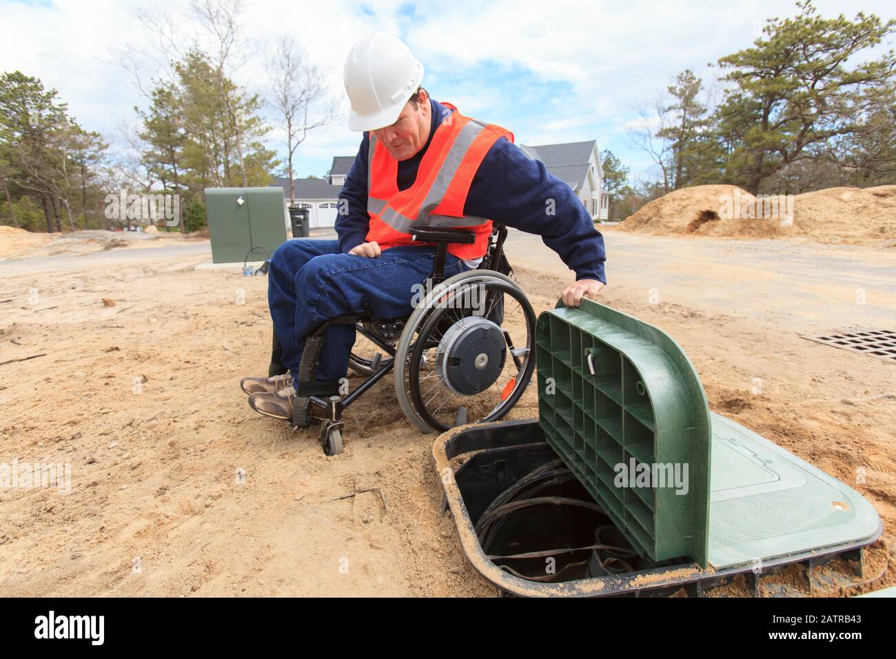 Man in wheelchair working on underground cables Stock Photo