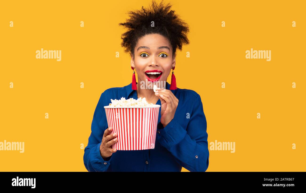 Millennial afro woman with popcorn watching movie Stock Photo