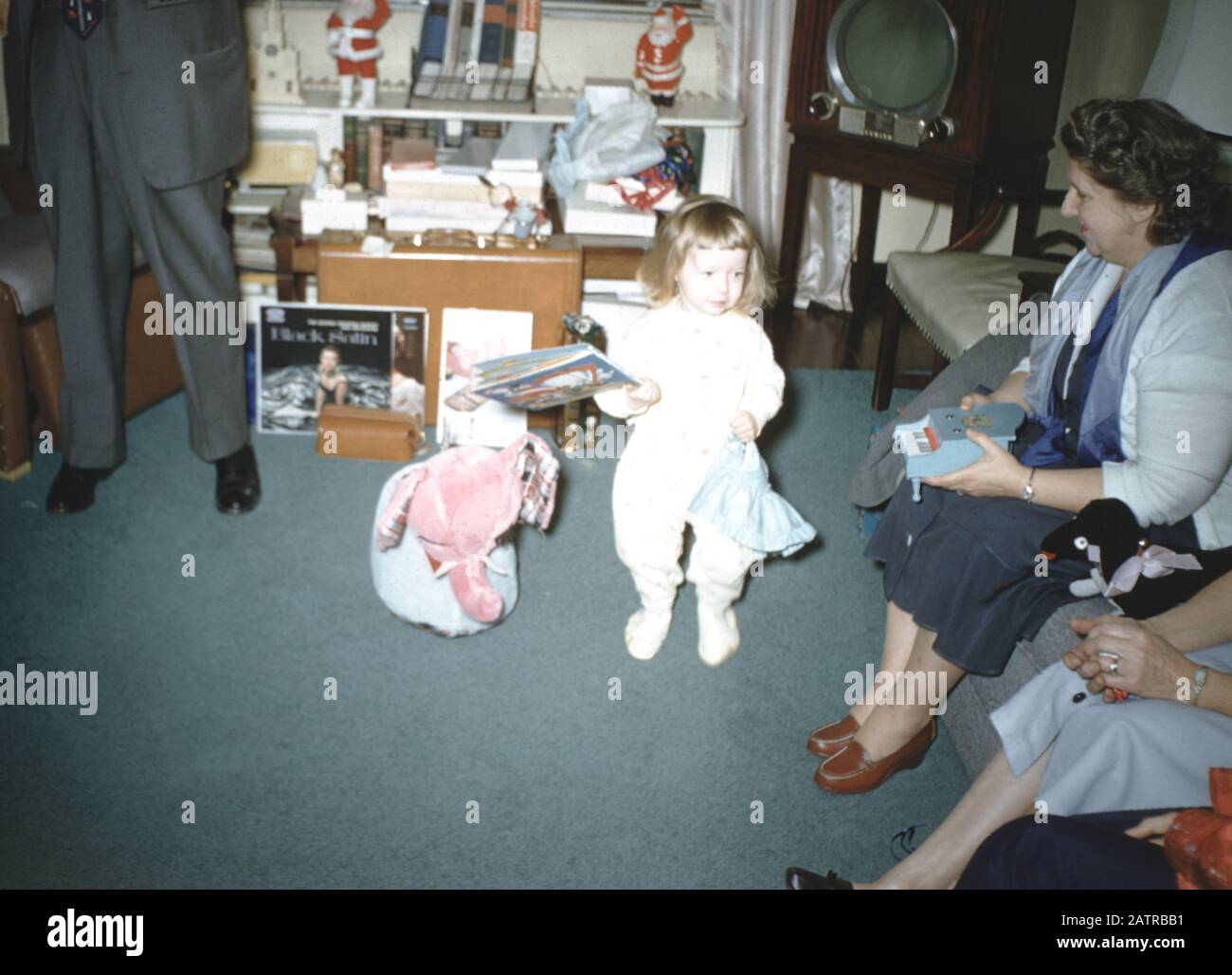 A family gathers and opens presents on Christmas Morning in a domestic home, with a copy of the album Black Satin by George Shearing quintet visible among the presents, 1960. () Stock Photo