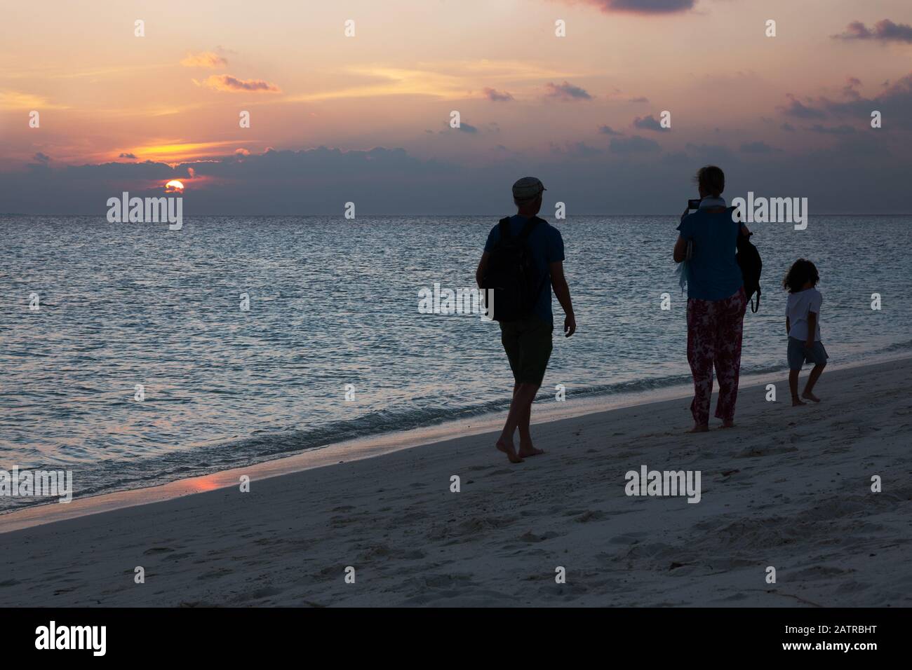 Family beach holiday; - a Family walking on the beach at sunset, the Maldives, Asia Stock Photo
