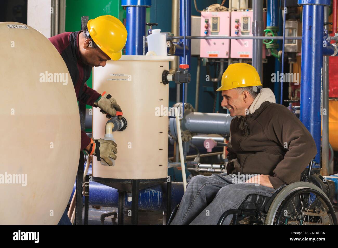 Disabled worker and a co-worker working in an industrial workplace Stock Photo
