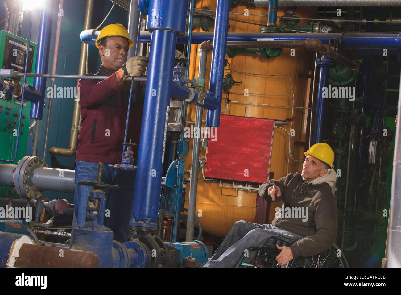 Disabled worker and a co-worker working in an industrial workplace Stock Photo
