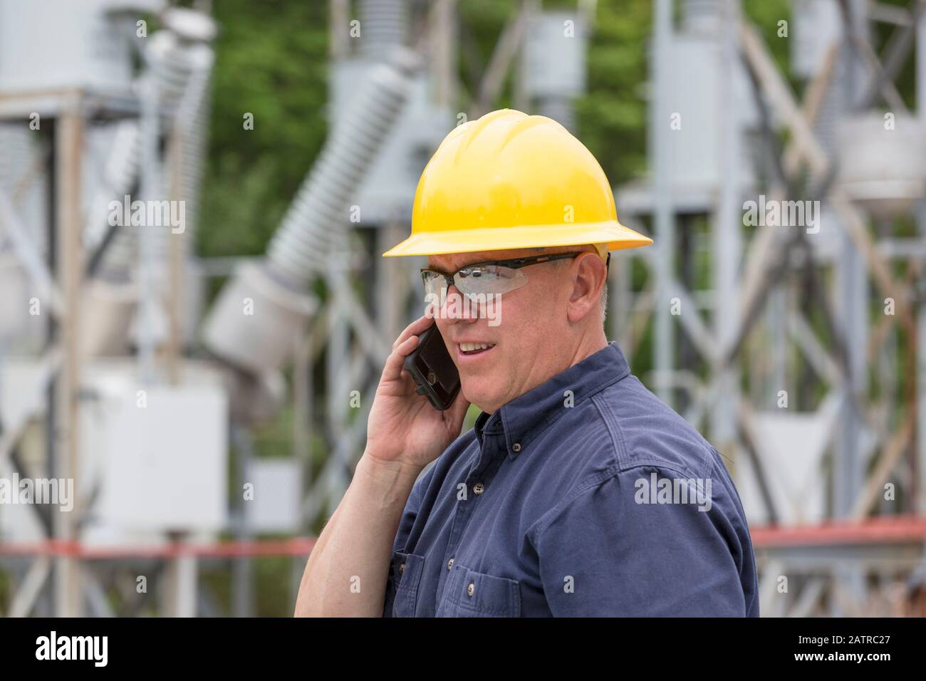 Tradesman talking on the phone at an electrical substation Stock Photo