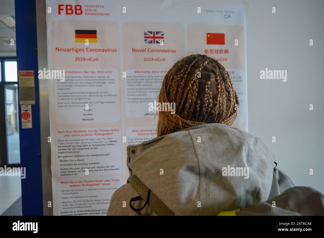 Berlin Airport SXF, Germany - 02/01/20: A passenger reads a warning billboard about Coronavirus 2019-nCoV. Written in German, English and Chinese Stock Photo