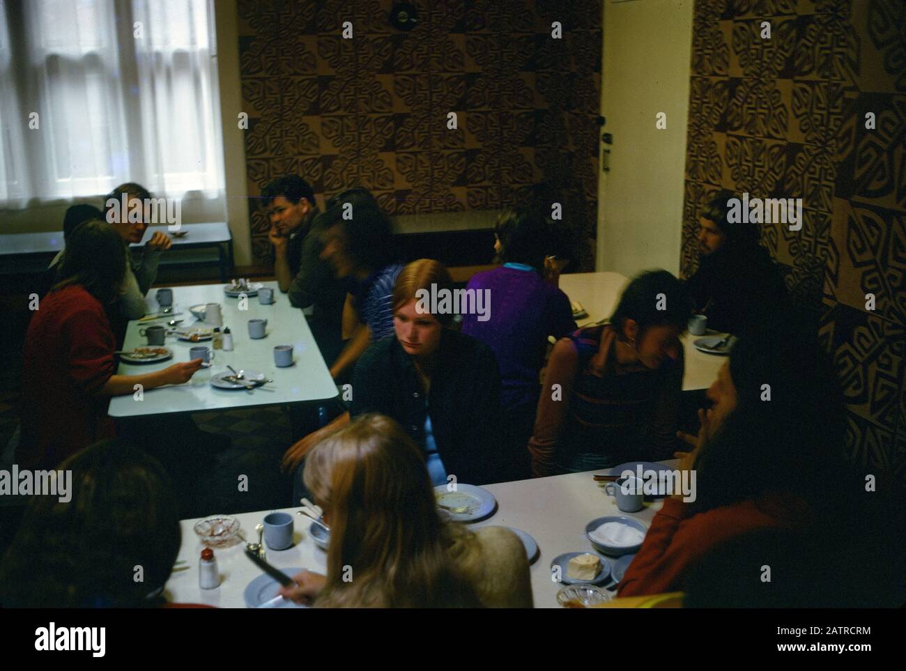 People dine indoors at a youth hostel, 1970. () Stock Photo