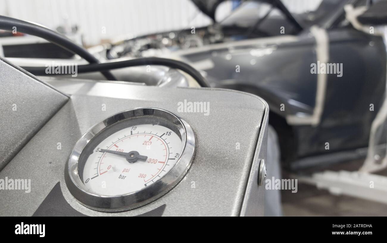 pressure gauge for checking the car's air conditioner against the background of a disassembled car Stock Photo