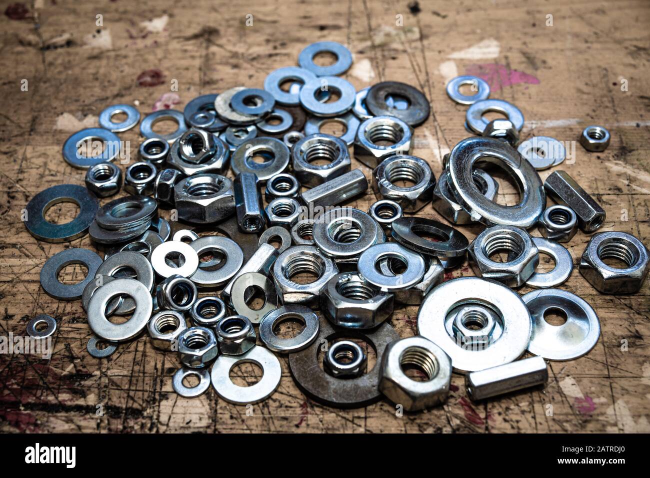 Assorted nuts and washers on wooden workbench stained grunge textured