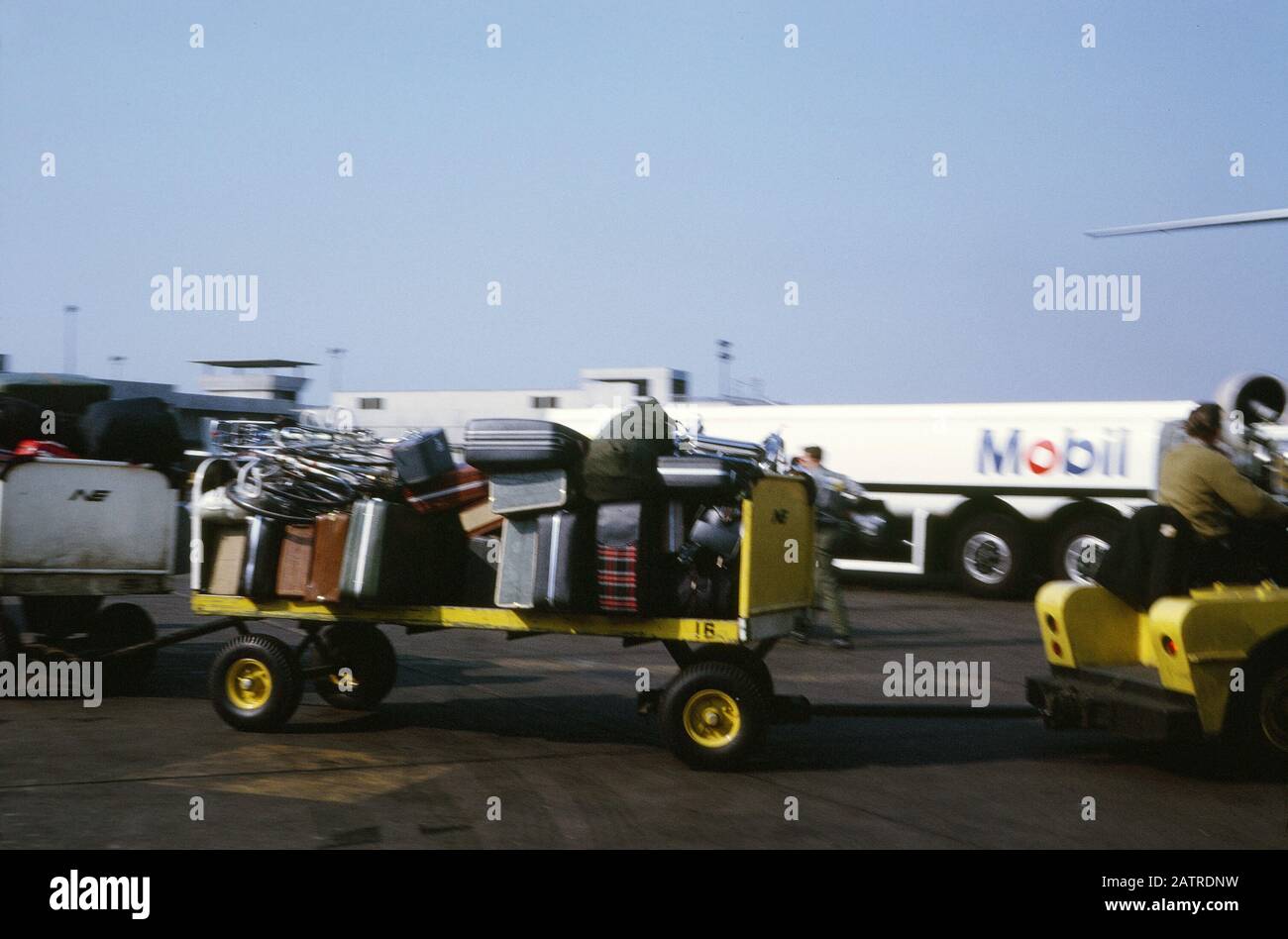 Vernacular photograph taken on a 35mm analog film transparency, believed to depict white and black utility truck from Mobil petroleum company on an airport tarmac, 1970. Major topics/objects detected include Vehicle, Aircraft, Air Force, Airplane and Truck. () Stock Photo