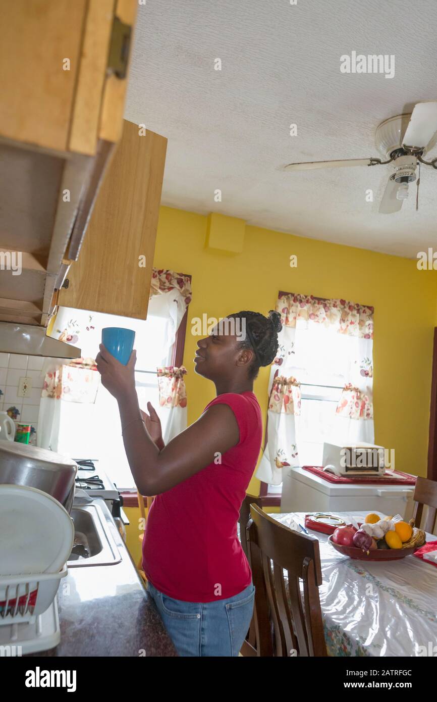 Teen suffering from Bipolar Disorder putting dishes away Stock Photo