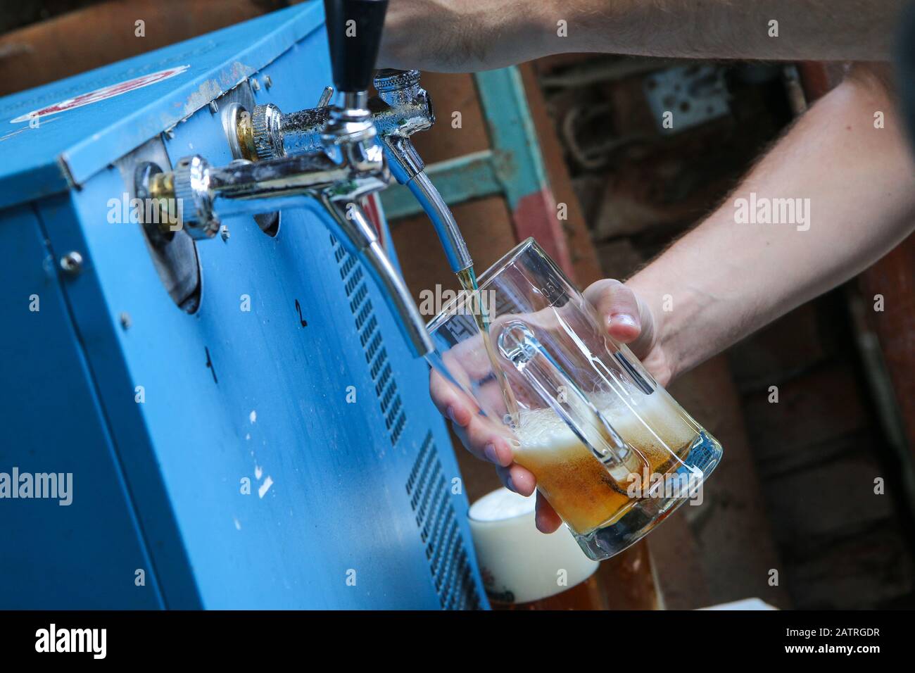 The detail of the hands of a guy at the bar. Self taping his beer from the taping equipment. Stock Photo