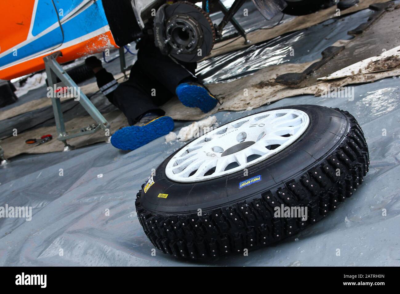 A detail of the tyre with studs used for the rally cars to have a better control on snow and ice. Lies in front of the car. Stock Photo