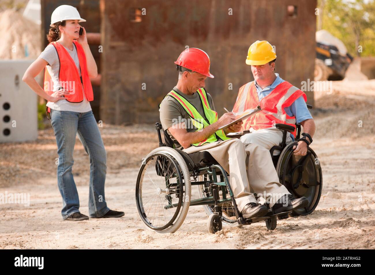 Construction job site with men in wheelchairs and woman talking on the phone Stock Photo