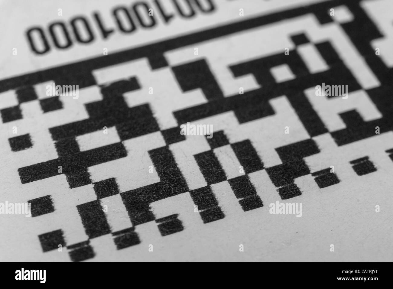 Abstract monochrome close up of isolated printed QR data matrix bar code on white paper label background from material inventory tracking system Stock Photo