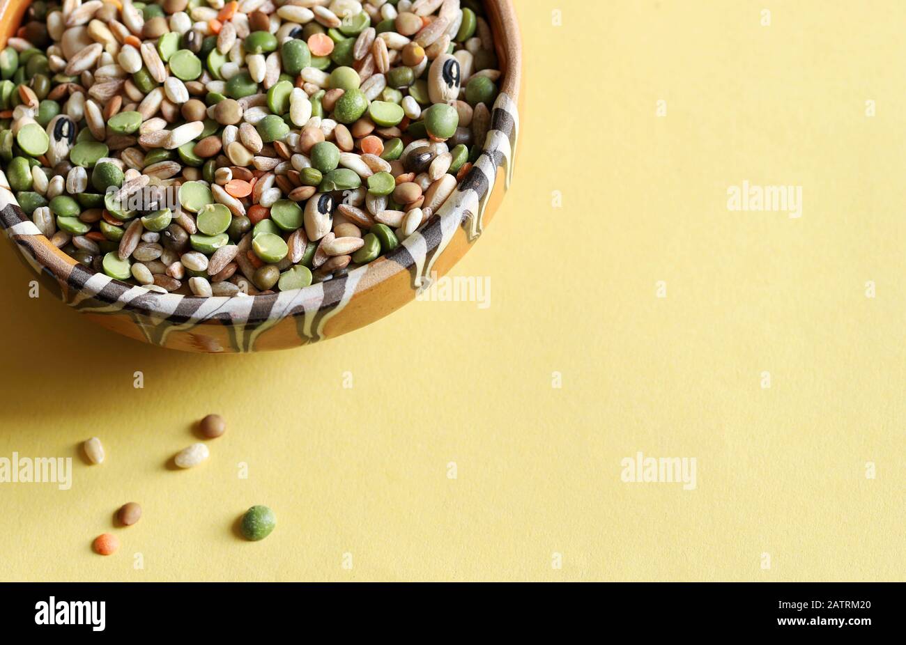 Mixed dried legumes in the bowl isolated on a yellow background.Top view. Stock Photo