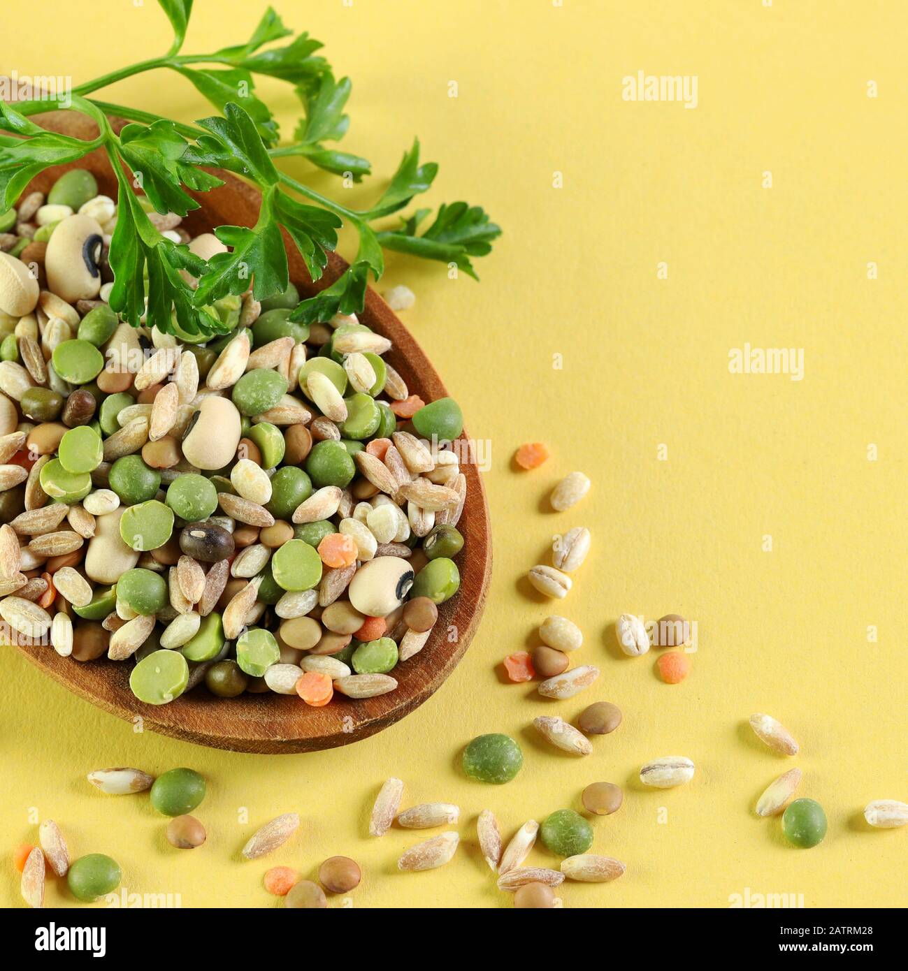 Mix of dried legumes in a wooden spoon isolated on yellow background. Top view. Stock Photo