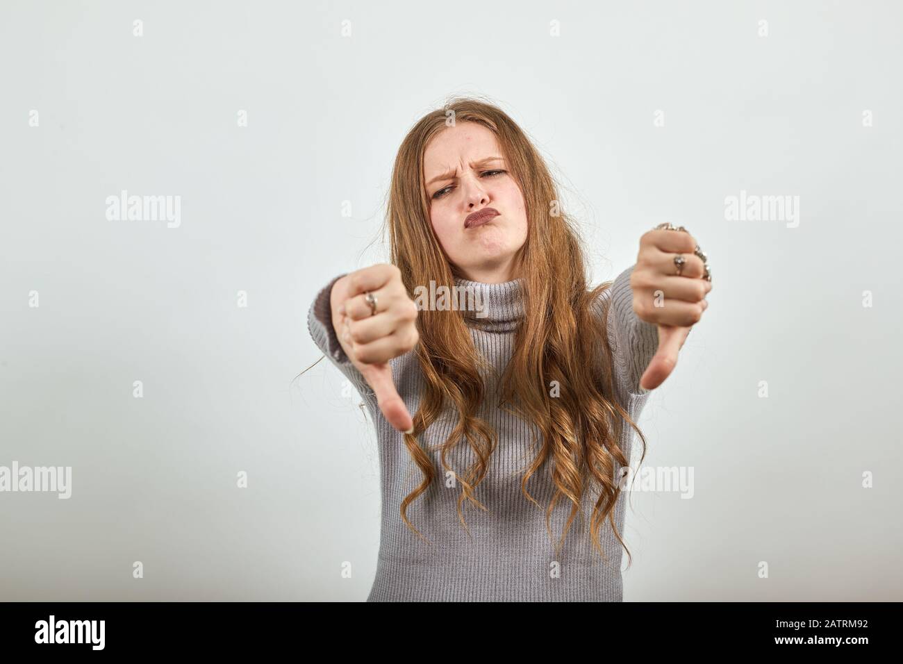 woman in grey sweater an enraged girl returns thumbs down demonstrates anger Stock Photo