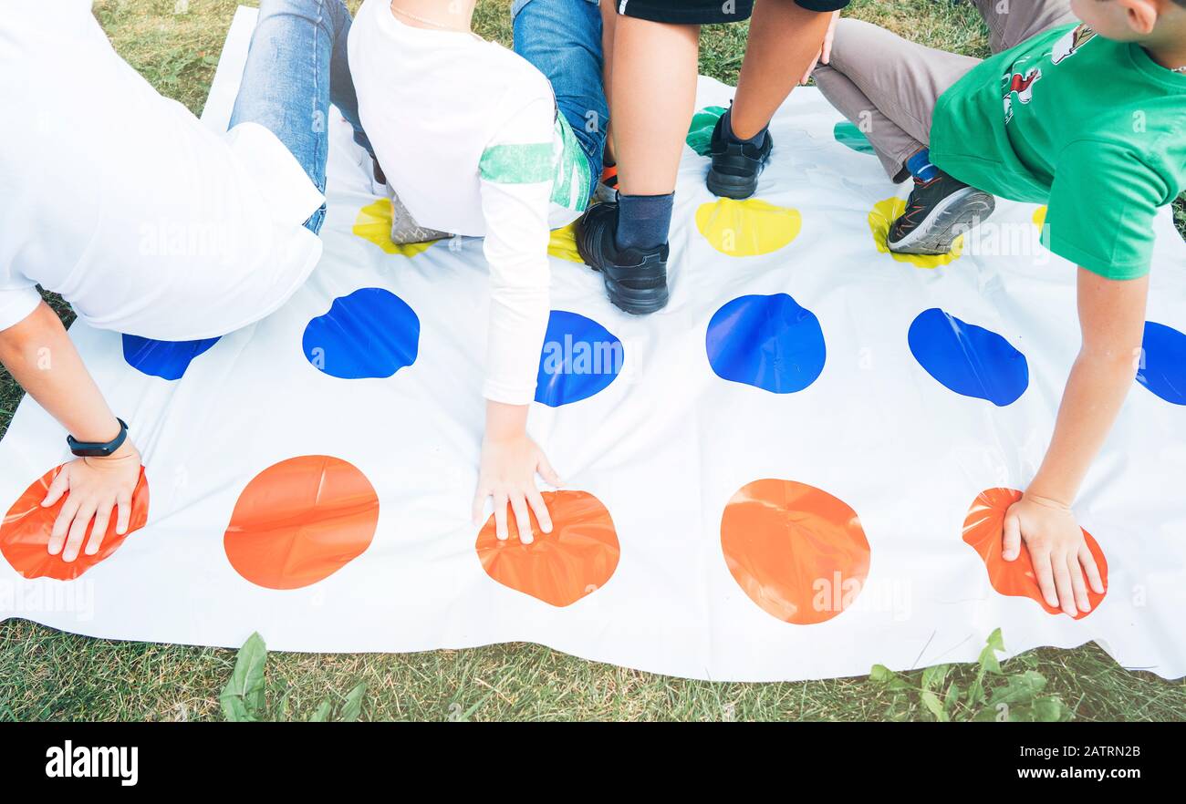 Children playing a twister on the grass. Hands on red Stock Photo Alamy