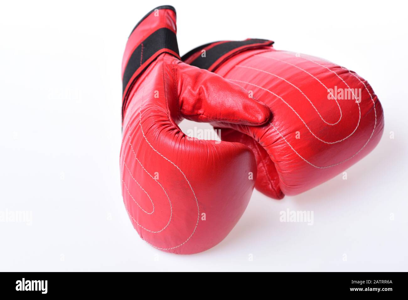 Pair of boxing gloves lying next to each other. Boxing gloves in red color  isolated on white background. Leather box equipment for fight and training.  Protection and strength concept Stock Photo -